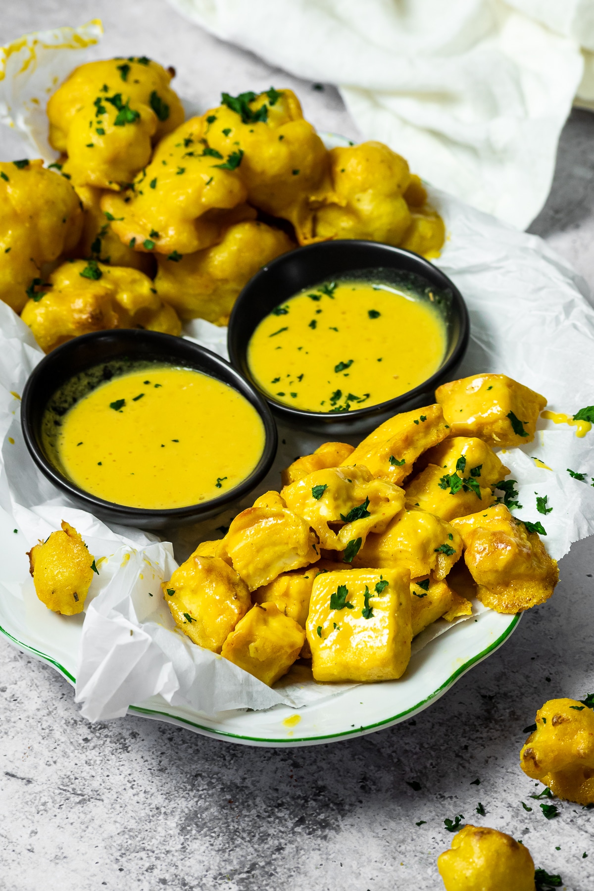 Serving plate with honey mustard cauliflower wings and tofu wings with two dipping bowls.