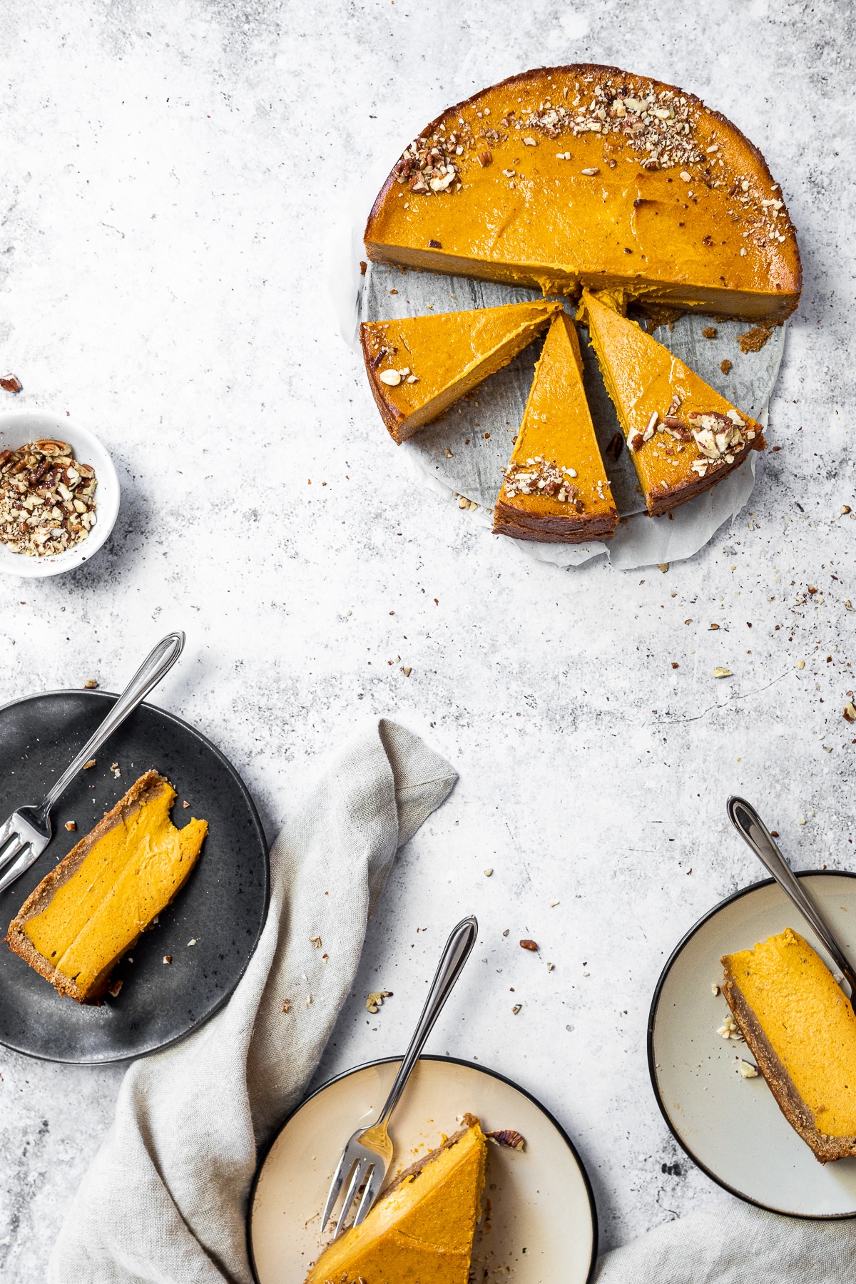 Bird view of 3 pieces of pumpkin cheesecake on 3 plates and the whole cake on a platter