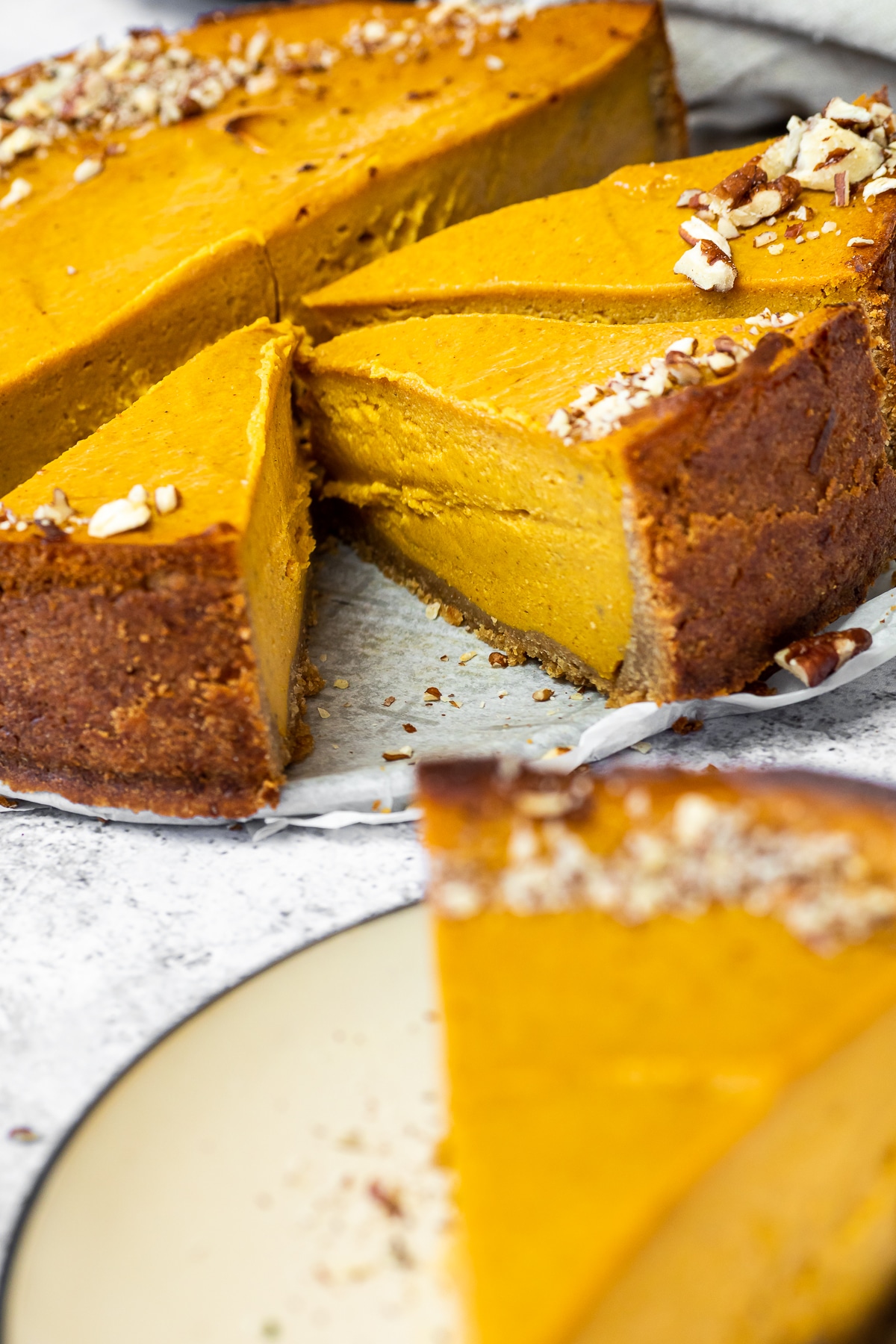 3 Cutted pumpkin Cheesecake pieces in focus with one blurred in front.