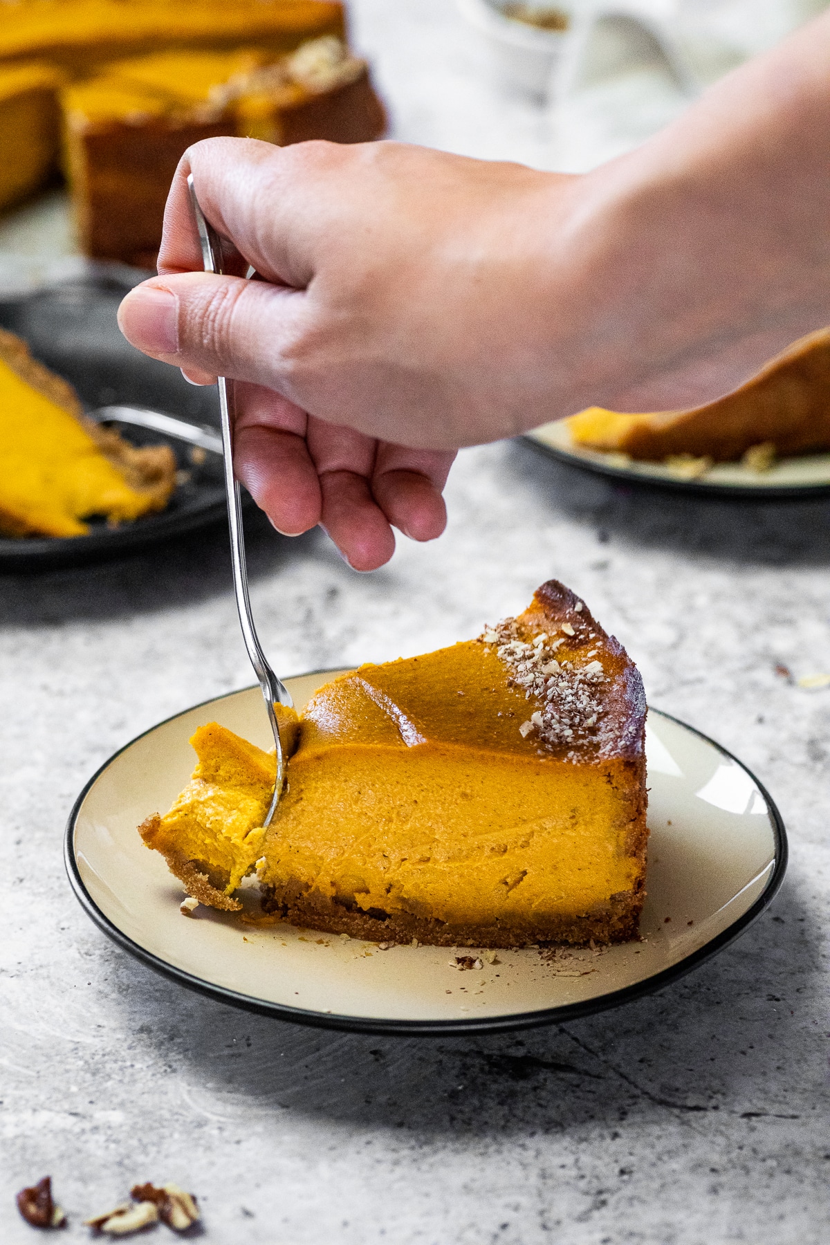 Taking some pumpkin cheesecake with a fork from a piece on a plate.