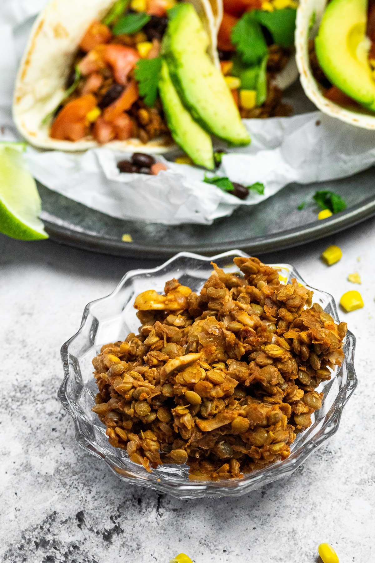 Vegan Taco Meat in a bowl with tacos in the background blurred.