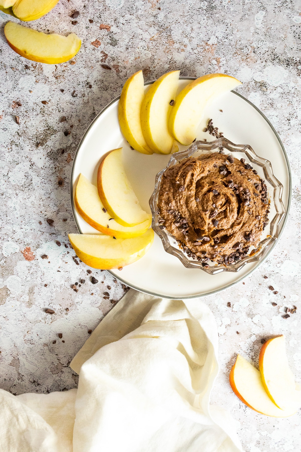 Bird view of a plate with sliced apples and a bowl with vegan brownie batter hummus