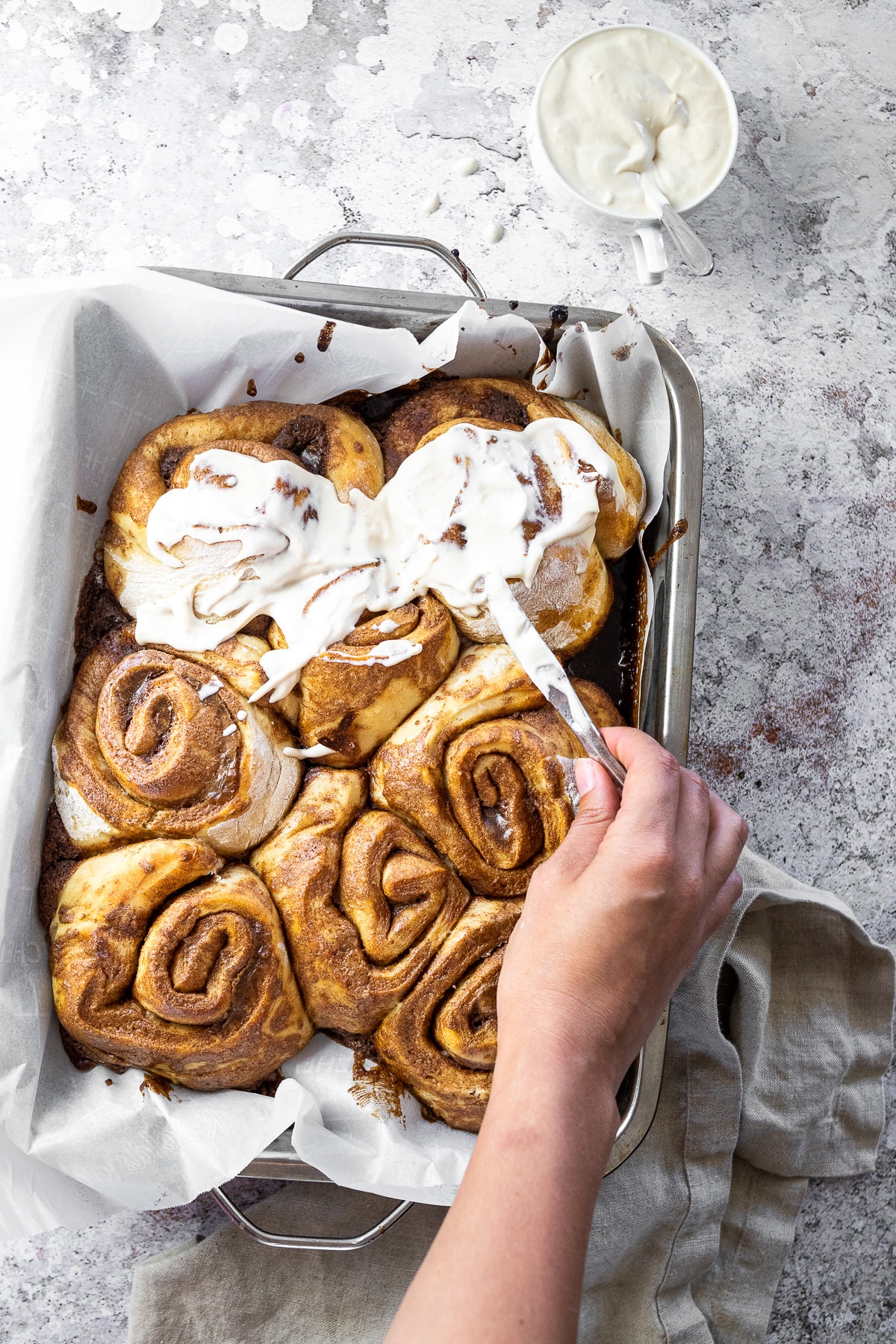 Birdview of vegan cinnamon buns with spreading some icing on them.