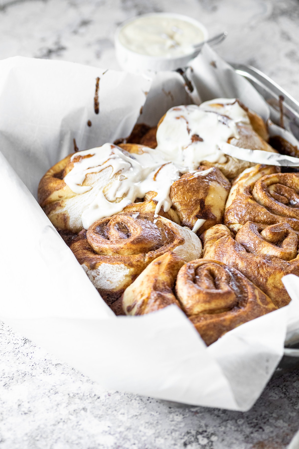 75 ° Winkel einer Pfanne mit Zimtschnecken und einige sind mit Frosting belegt