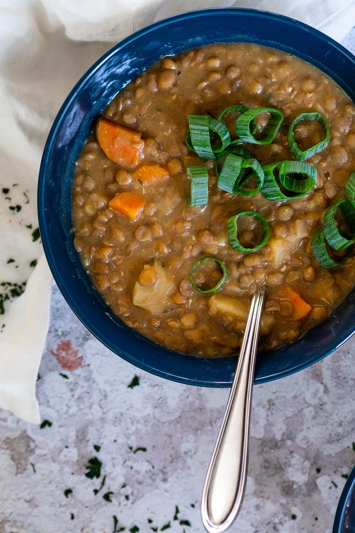 Vogelansicht der Linsensuppe, die in einer Schüssel serviert und mit einigen Frühlingszwiebeln garniert wird