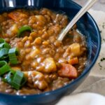 Gerade Ansicht auf einer Schüssel mit Linsensuppe und einem Löffel in dieser Schüssel.