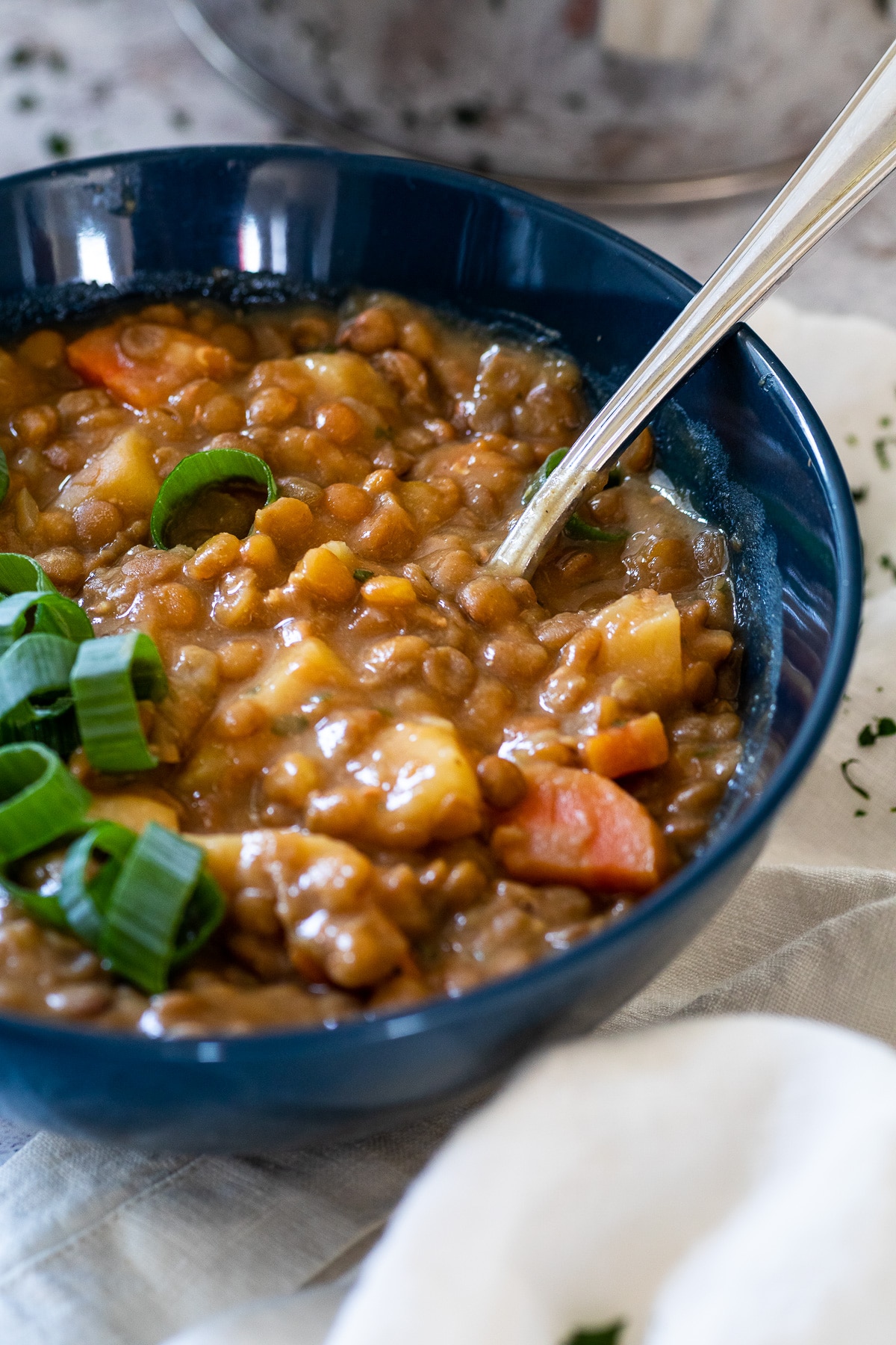 Straight view on a bowl with lentil soup and a spoon in that bowl.