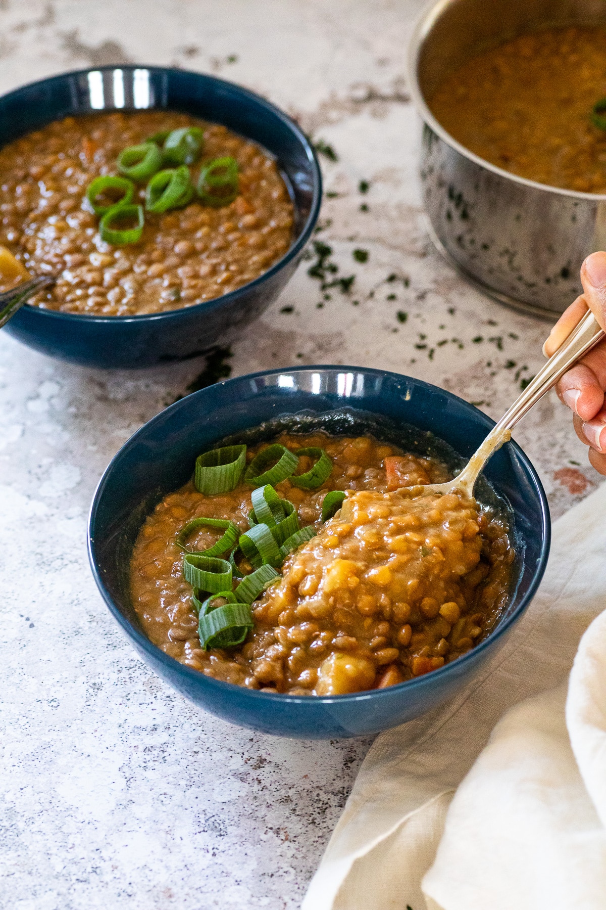 Ein Löffel wird über eine Schüssel mit Linsensuppe gehalten.