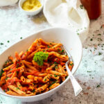 Bowl of vegan penne alla vodka with ja sauce jar in the background