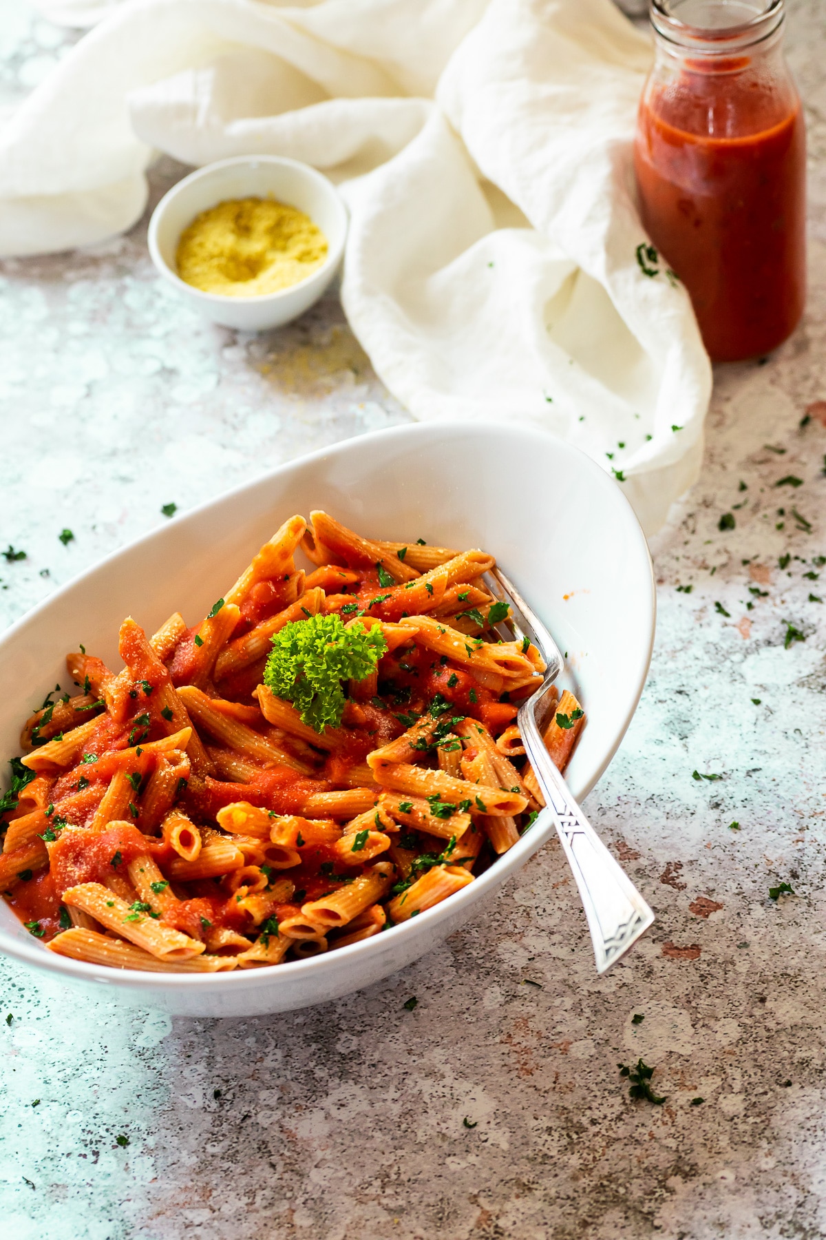 Schüssel veganen Penne alla Wodka mit Ja-Saucenglas im Hintergrund