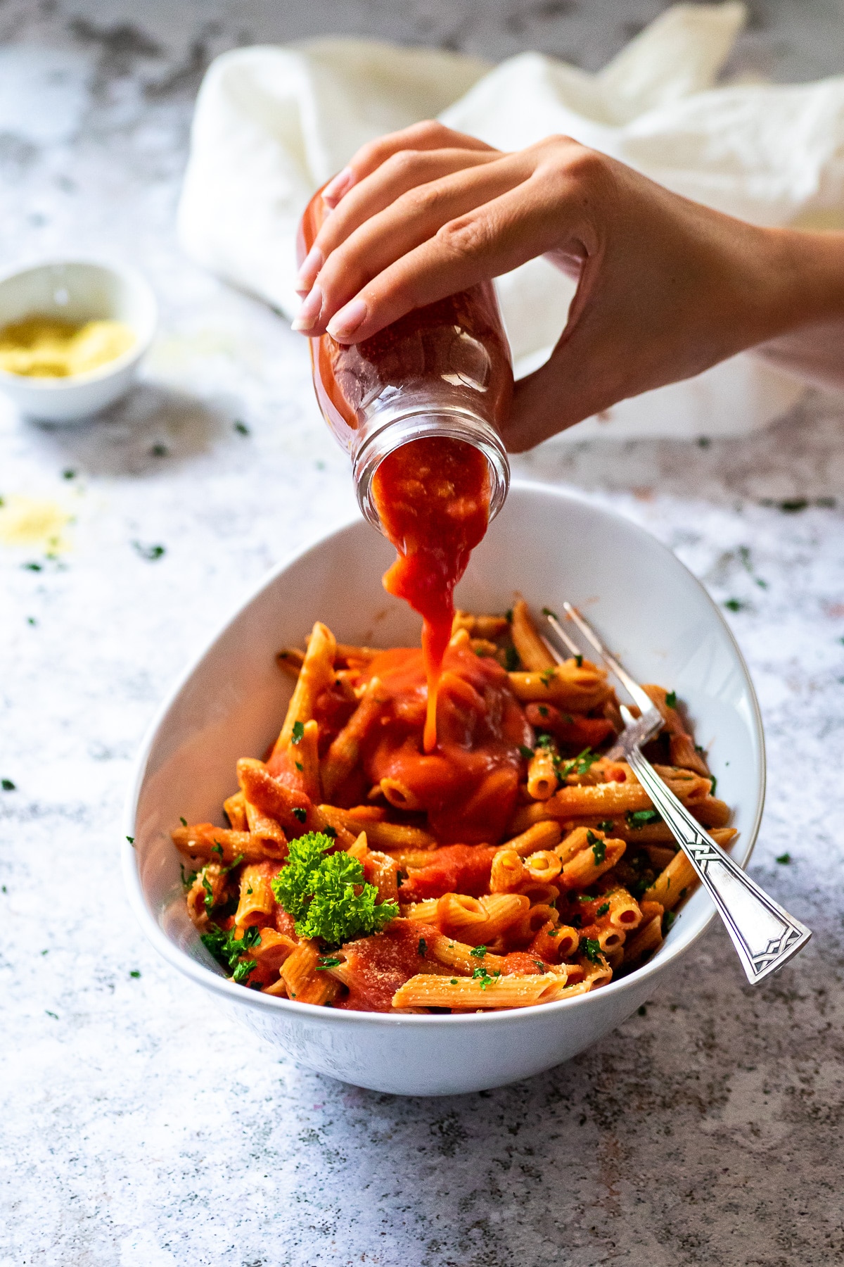 Pouring some tomato vodka sauce over penne