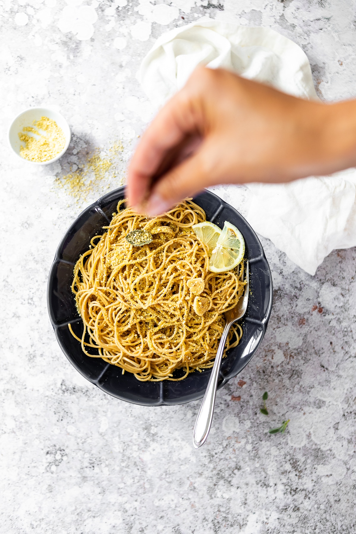 Vogelansicht einer Schüssel mit Salbei-Spaghetti mit etwas Käse darüber streuen