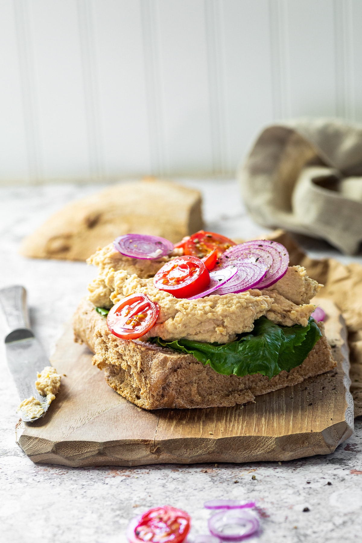 straight view on a vegan tuna sandwich toast topped with tomatoes and onions