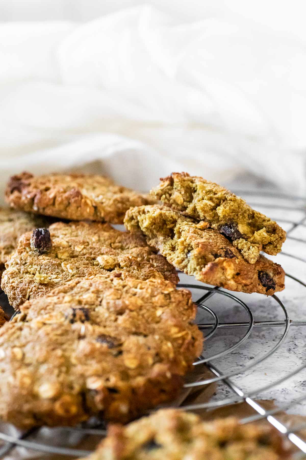 Focus on two halves of vegan oat cookies. Laying on a wire rack,