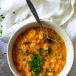 A bowl vegan sauerkraut soup with a spoon and cloth next to it.