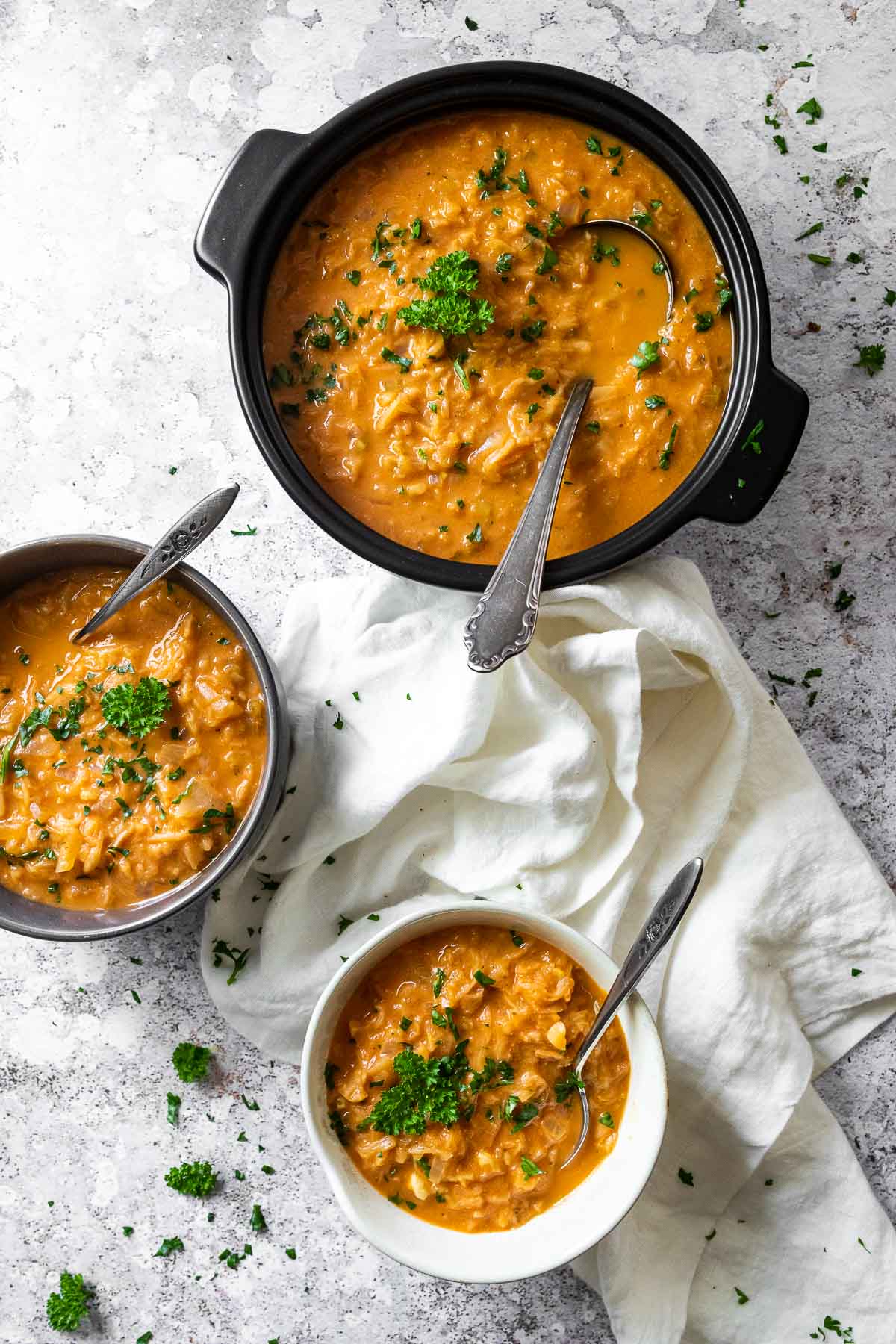 Vogelansicht von 2 Schalen mit veganer Sauerkrautsuppe und einem Topf mit Sauerkrautsuppe.