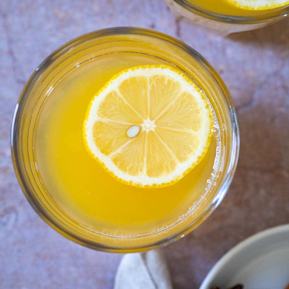 Bird view of a cup with warm lemonade with a slice of lemon floating.