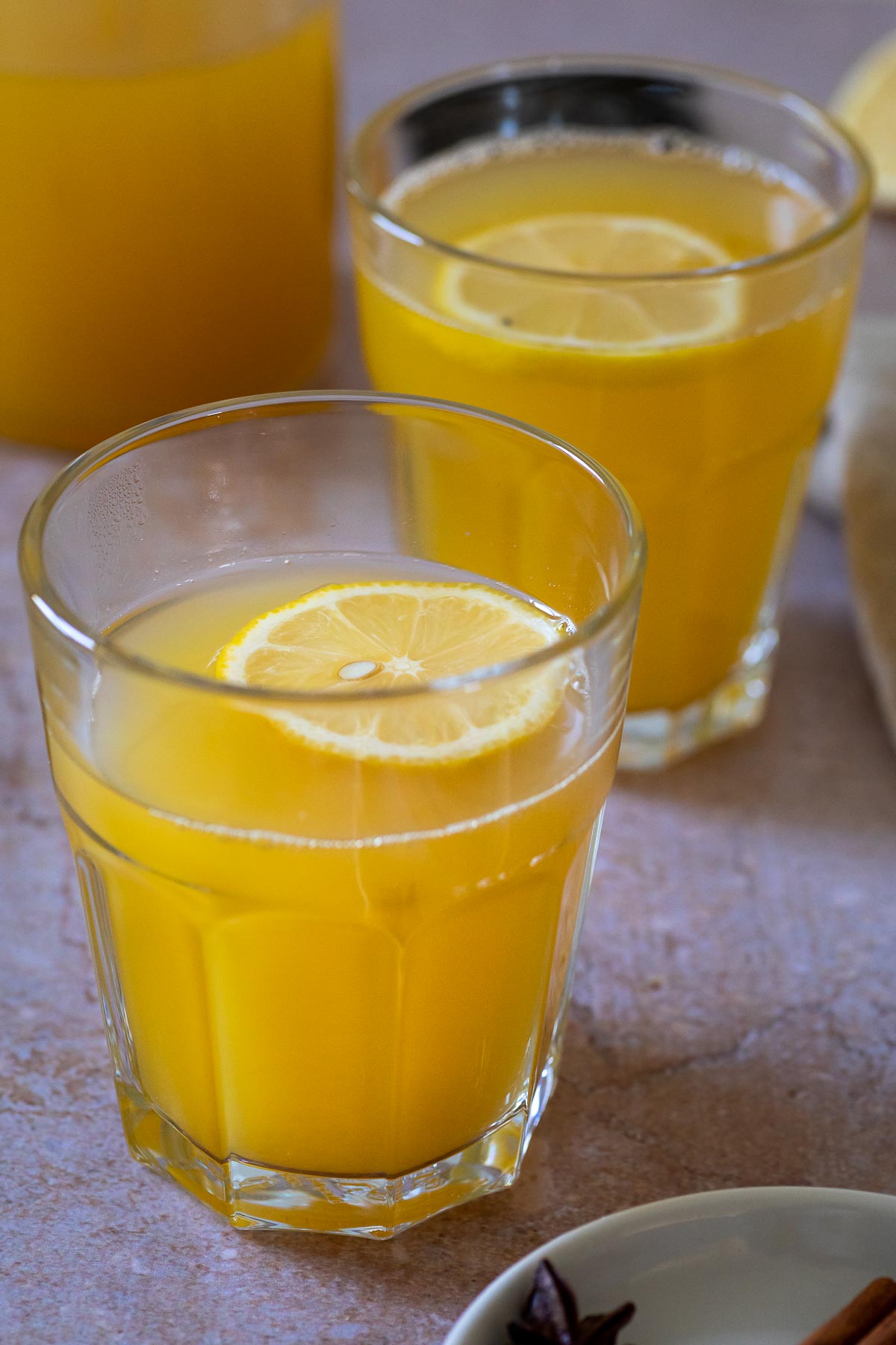 2 Gläser mit warmer Winterlimonade mit einer Zitronenscheibe darüber.