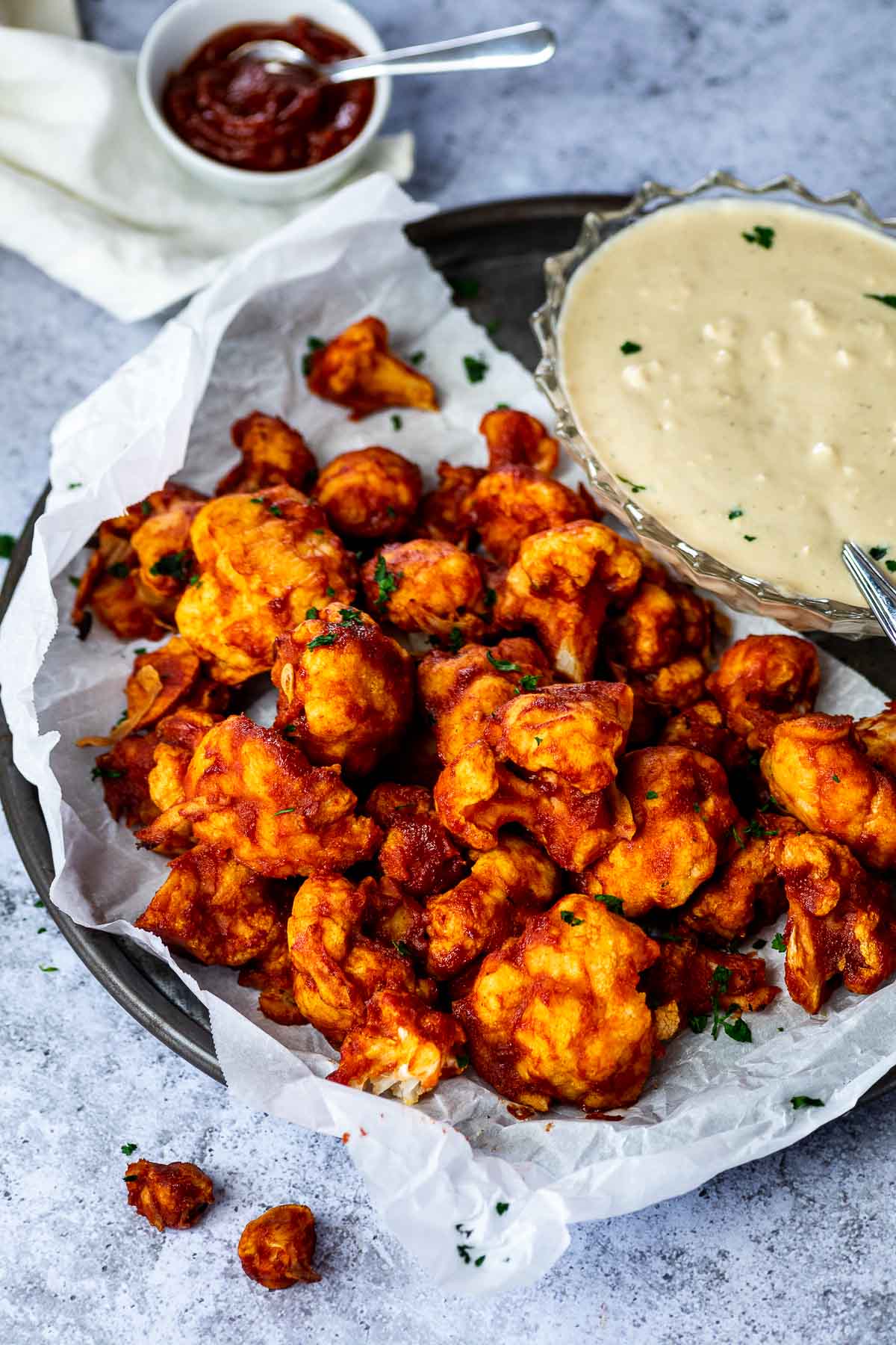 Vegane BBQ Wings auf einem Teller mit einer Schüssel veganem Blauschimmelkäse-Dressing und BBQ-Sauce