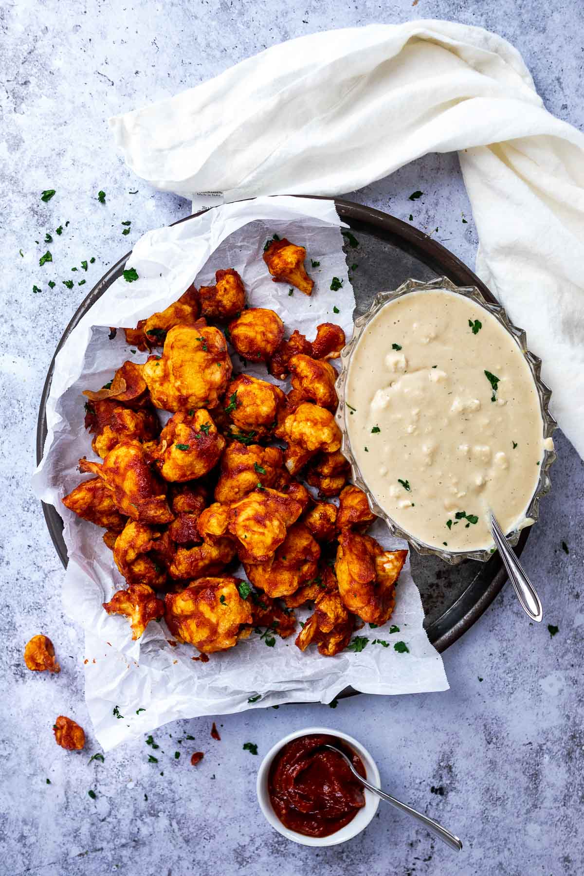 Vogelansicht einer Platte mit veganen BBQ Wings (Blumenkohlflügel) und einer Schüssel veganen Blauschimmelkäse-Dressings