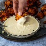 Einen Blumenkohl in veganes Blauschimmelkäse-Dressing tauchen