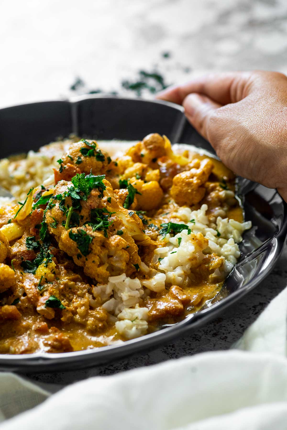 Holding the bowl with vegan butter chicken with rice. Close up