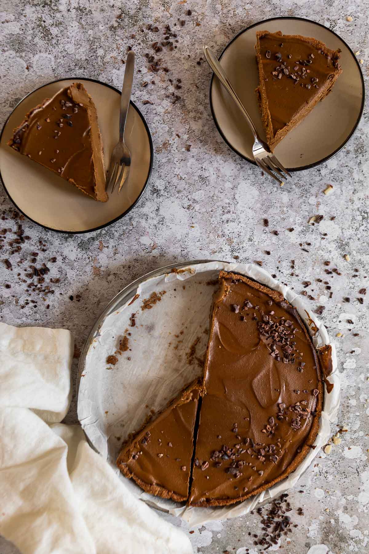 Bird view of a vegan chocolate pie on a plate with 2 pieces on little plates.