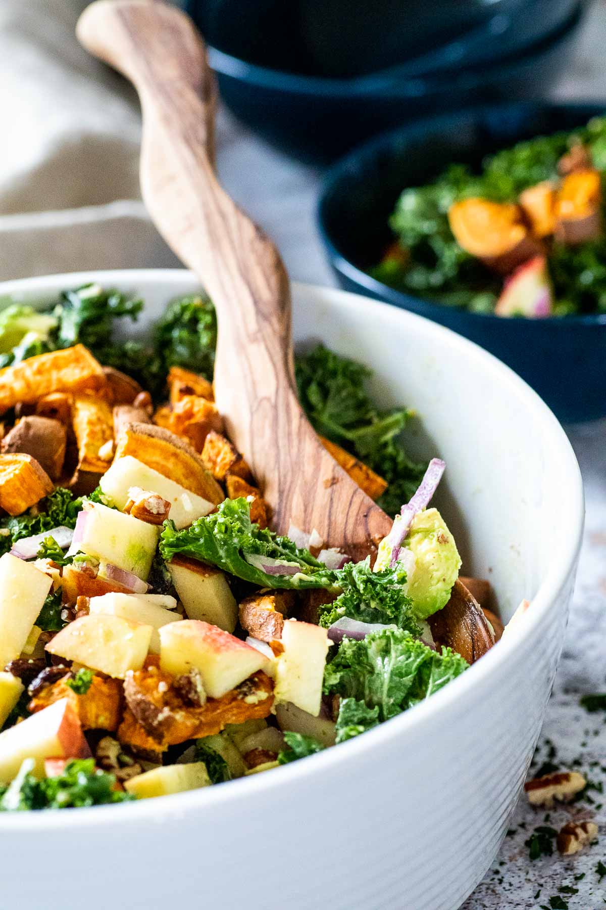 White bowl of kale salad with a serving spoon