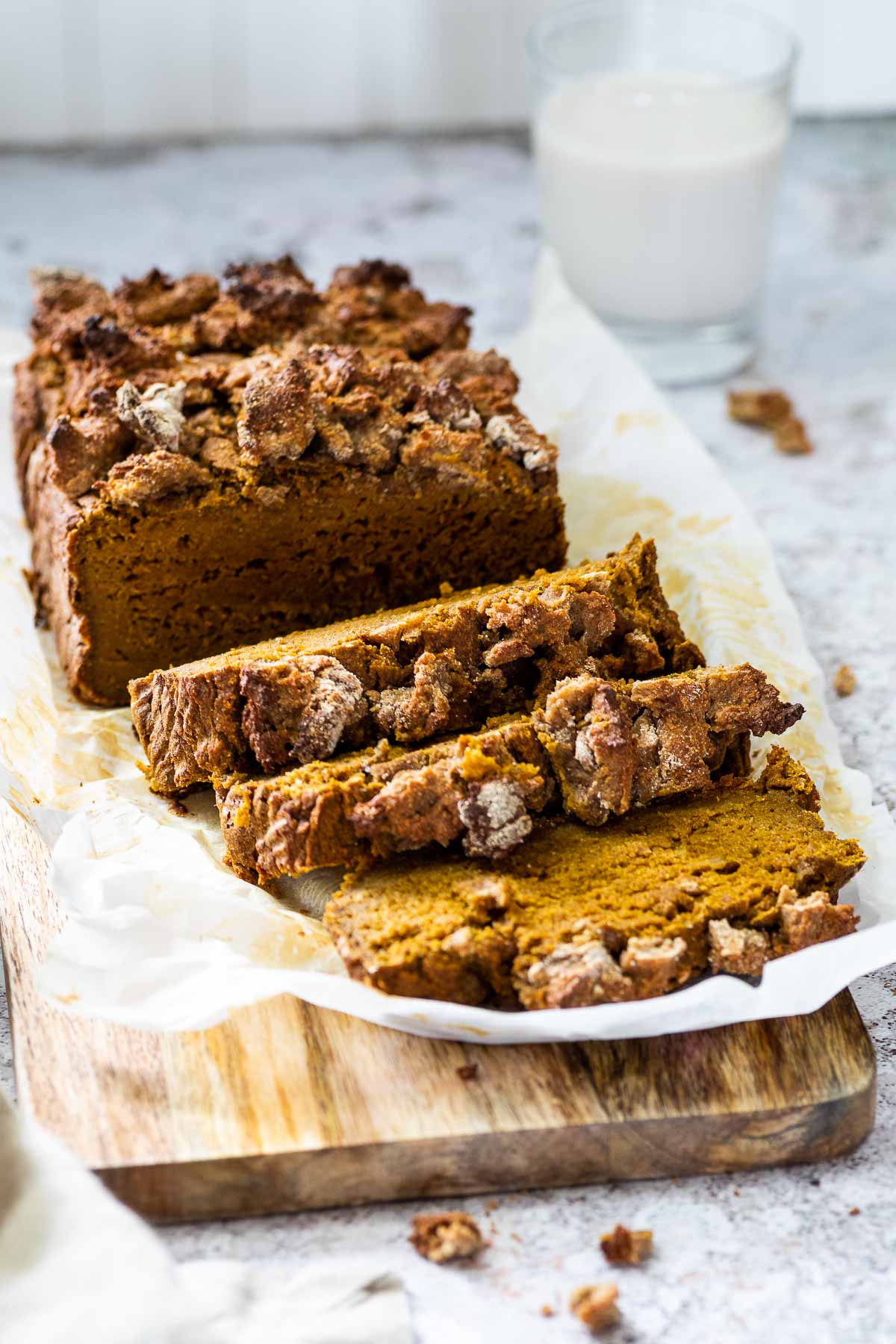 Veganes Kürbisbrot auf einem Holzbrett mit 3 Scheiben serviert.