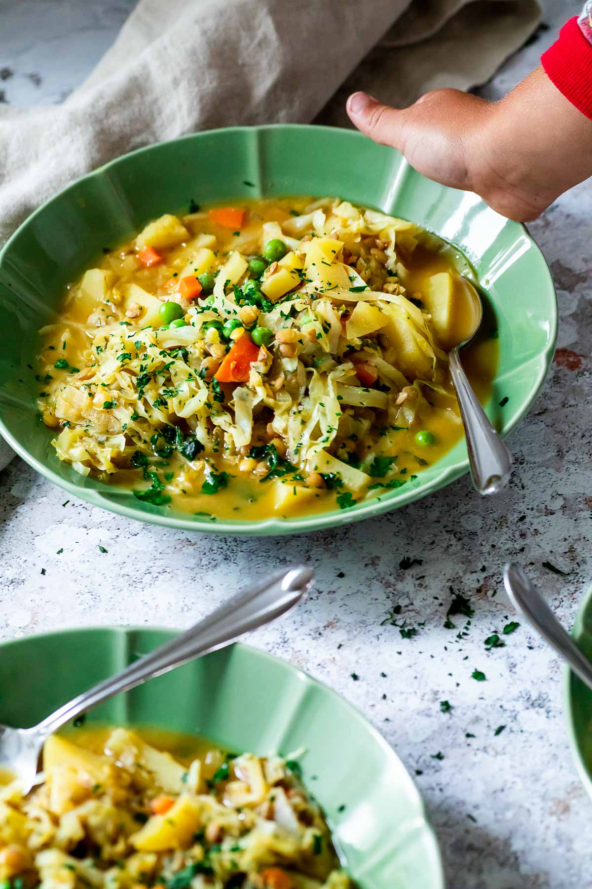 Kid hand is holding a bowl with lentil stew