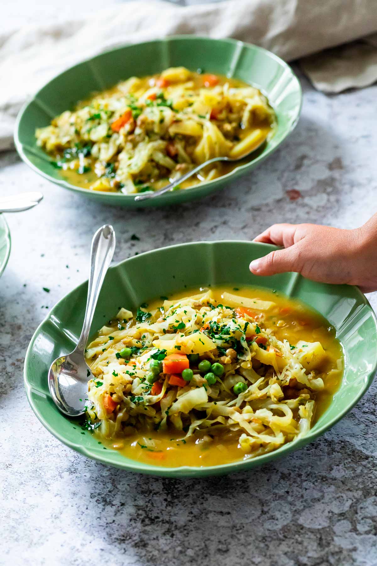 two bowls with winter stew and one bowl with a kid hand.