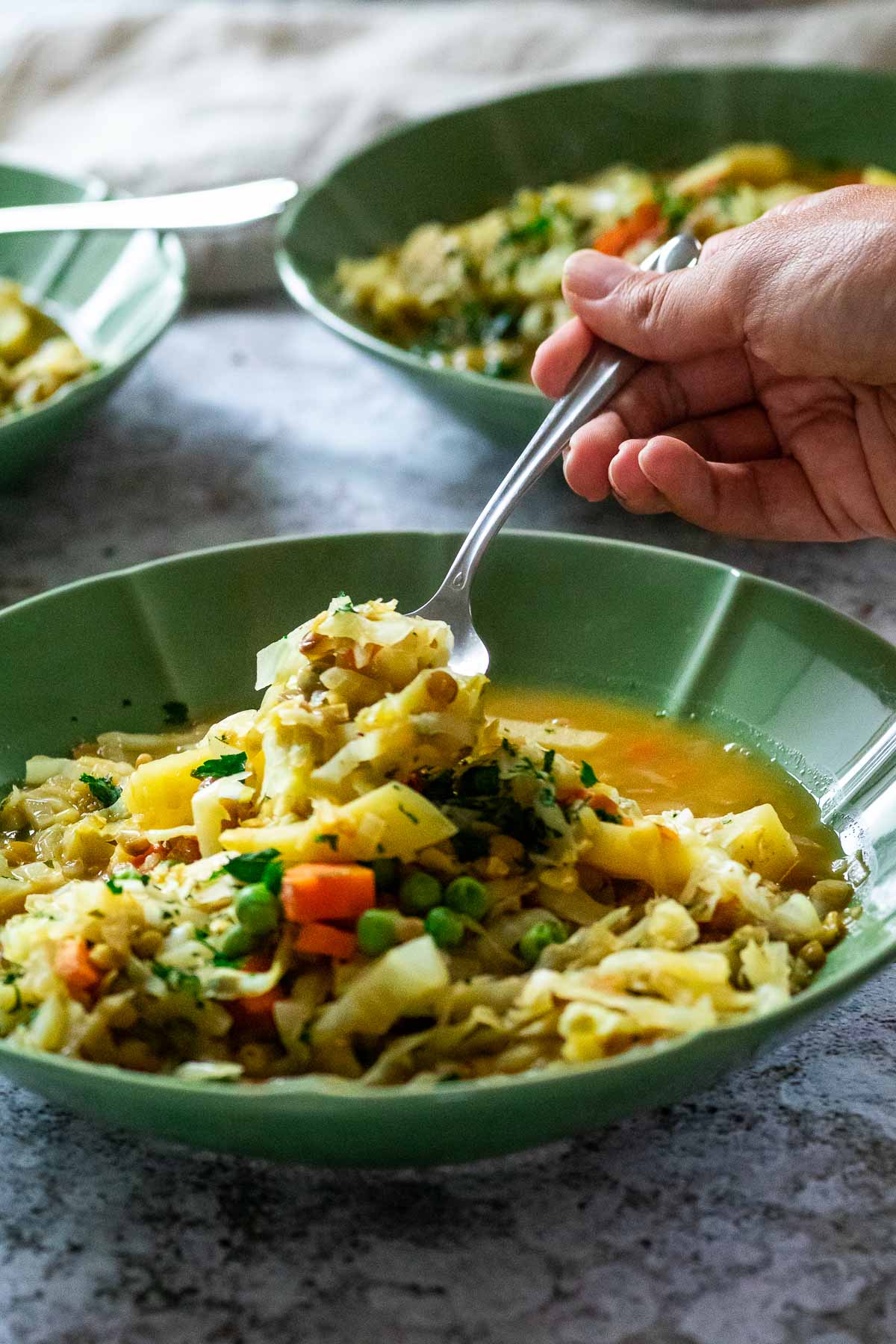 holding a spoon with winter stew over the bowl.