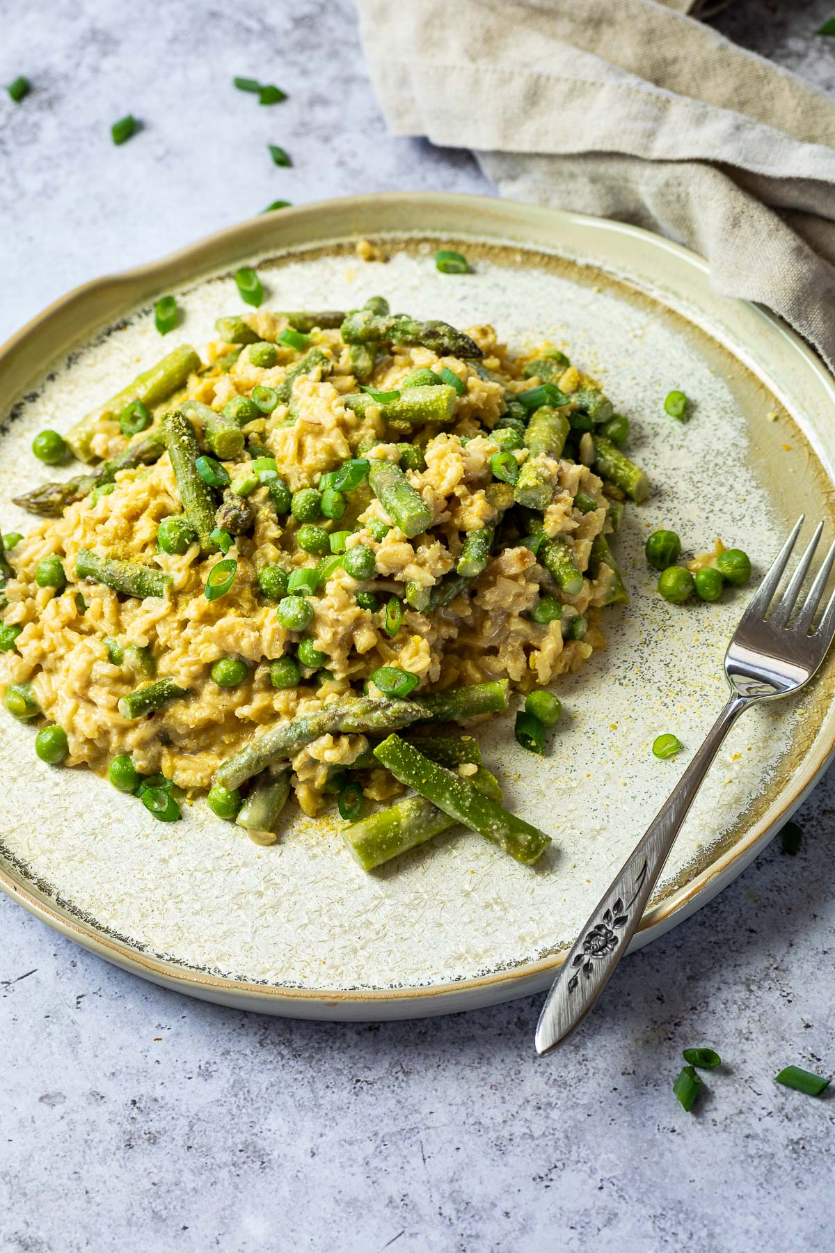 Veganes Erbsen-Spargel-Risotto auf einem Teller mit einer Gabel daneben.