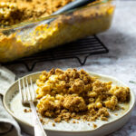 Vegan gebackener Mac und Käse auf einer Pflanze vor einem Auflauf.