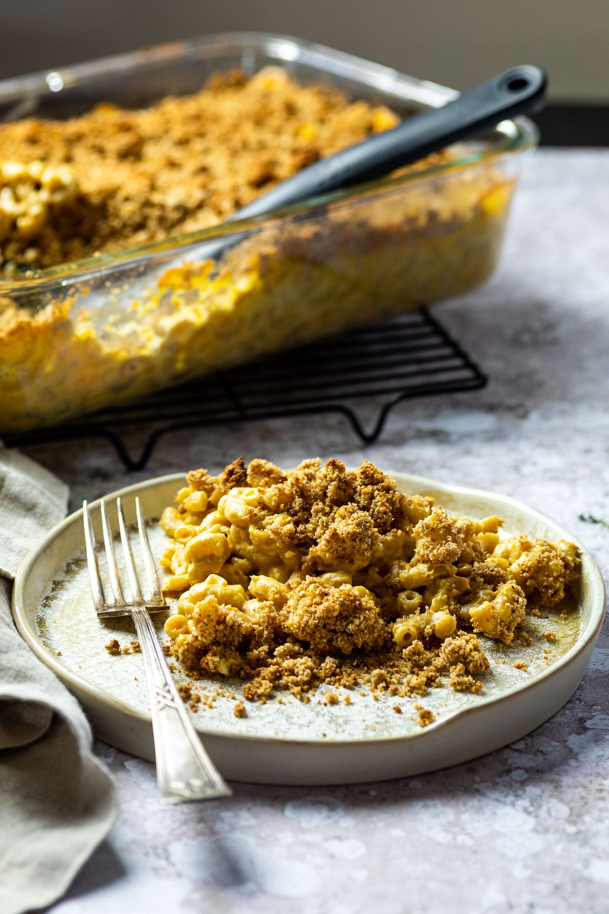 Vegan Baked mac and Cheese on a plant in front of a casserole.