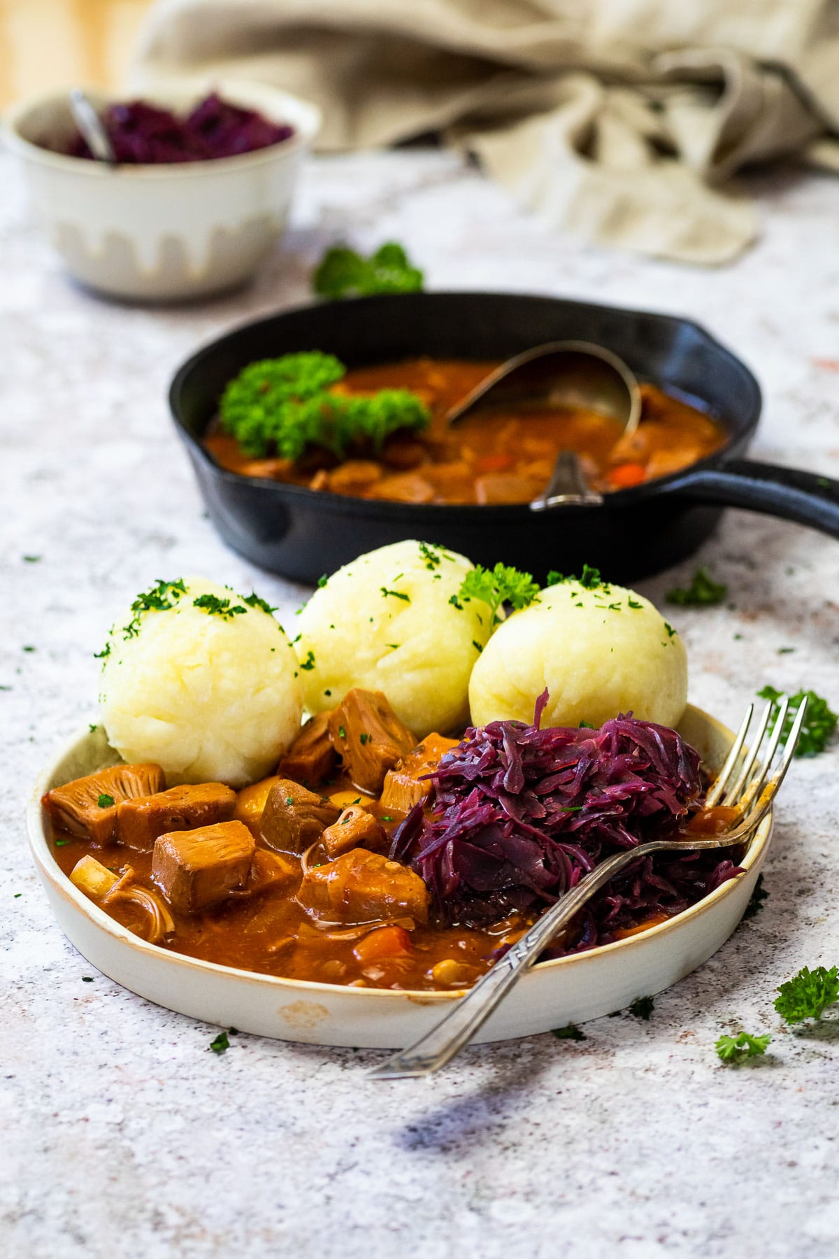 Eine Pfanne und ein Teller mit ungarischem Gulasch auf pflanzlicher Basis