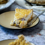 Piece of vegan Rice Pudding Pie on a plate in front of a pie pan and a plate. And in the back of a plate.