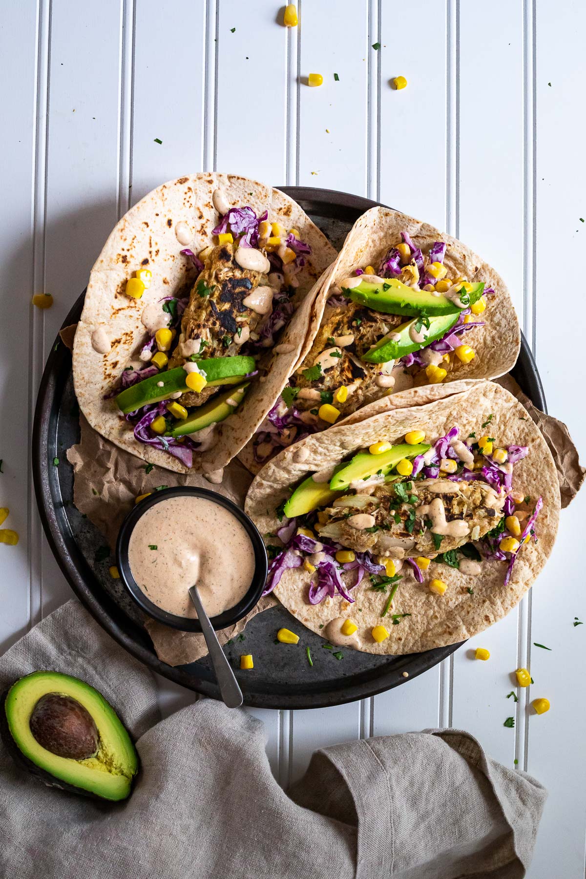 Bird View of a platter with 3 vegan fish tacos and a mini sauce bowl.