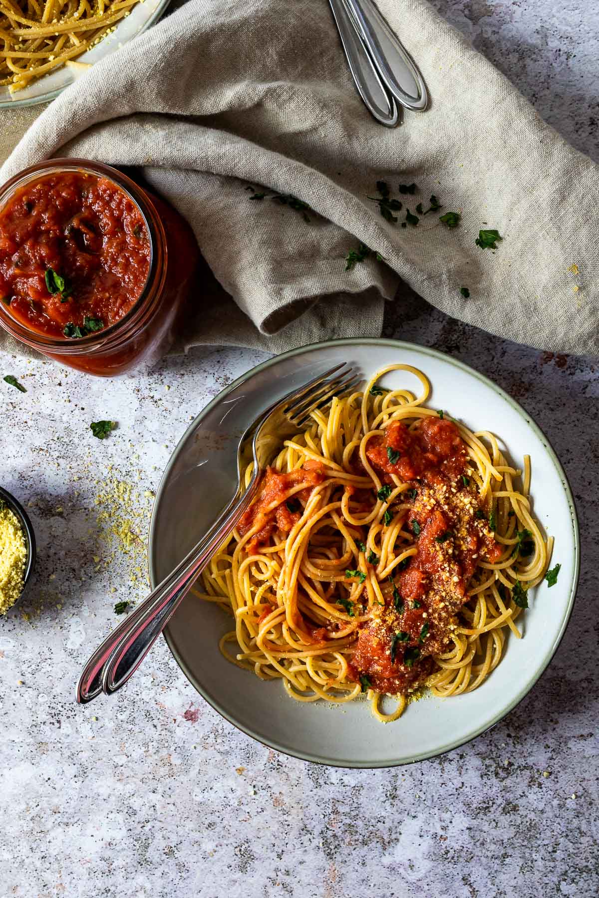 Spaghetti mit Marinara-Sauce in einer Schüssel mit einem Marinara-Glas daneben.