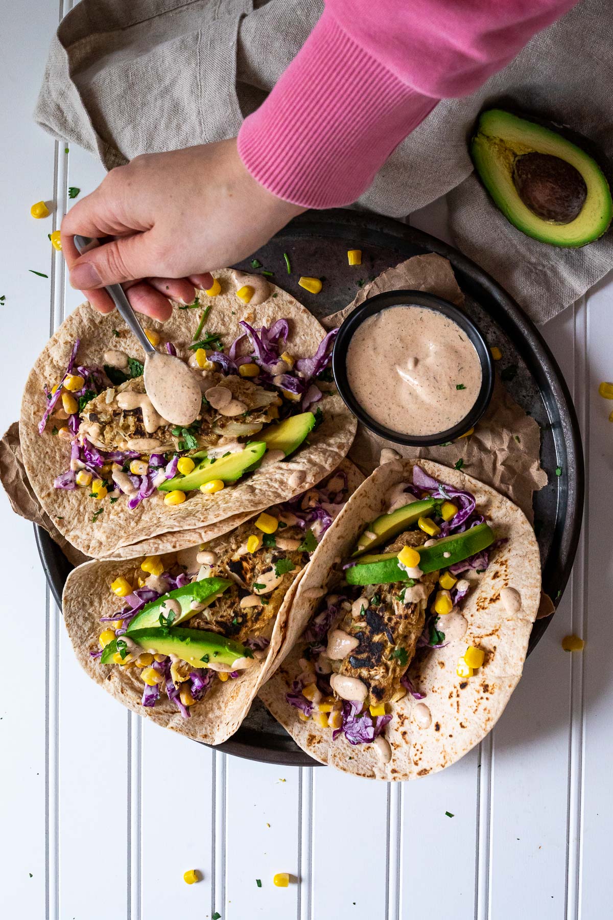 Vegane Fisch-Taco-Platte mit Sauce. Gießen Sie etwas Sauce über einen der Tacos.