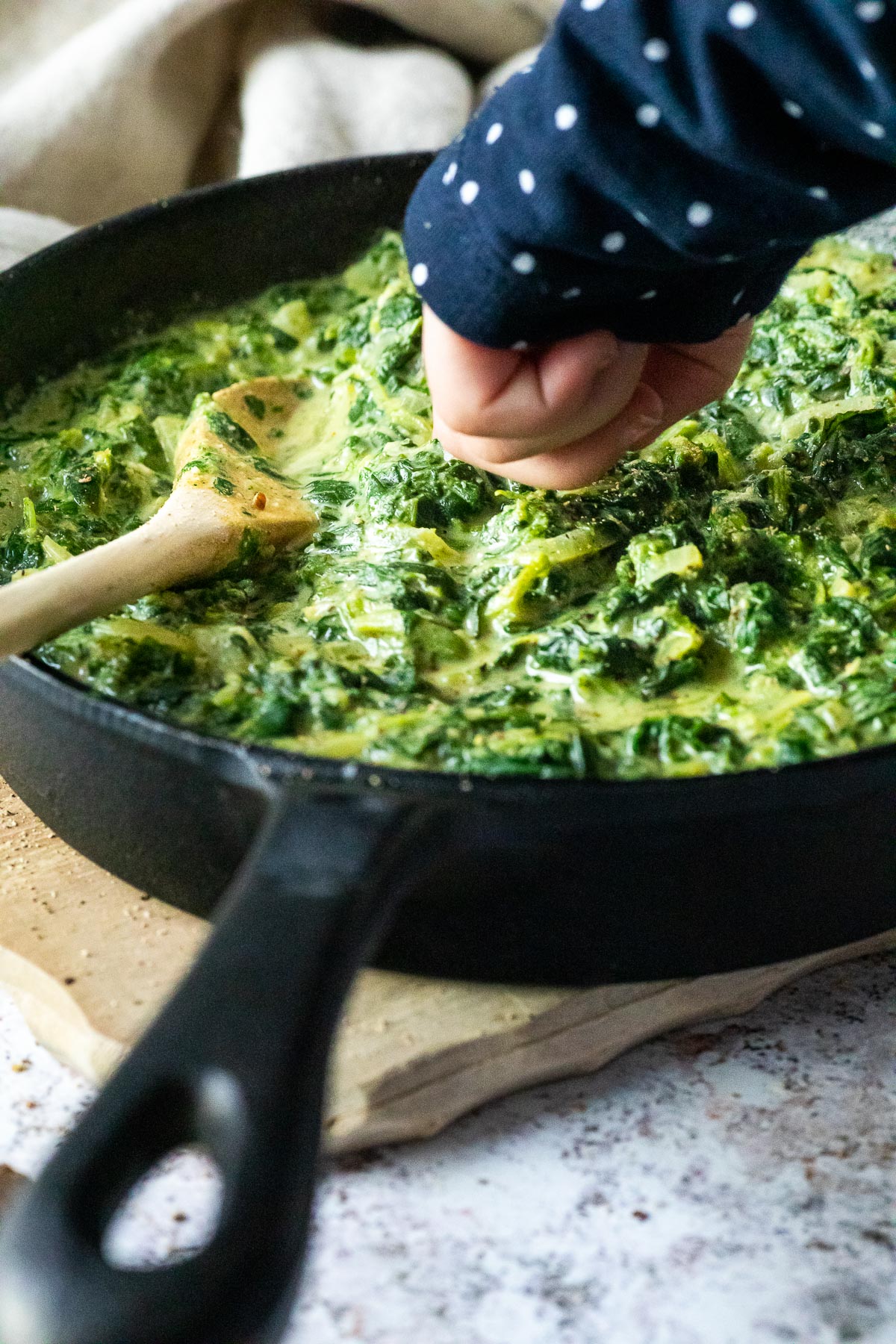 Child dips one finger in vegan creamed spinach