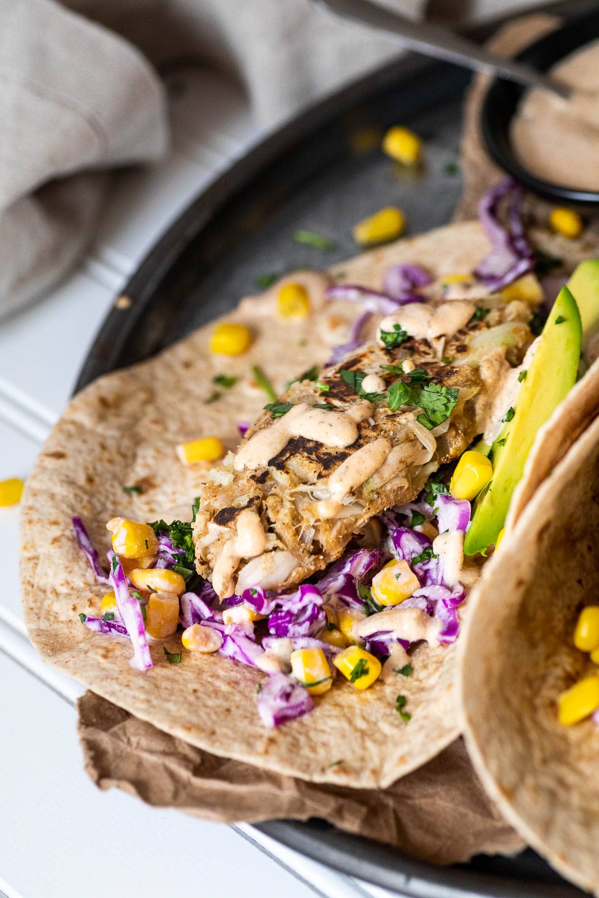 Ein veganer Fischstäbchen im Fokus wird in einem veganen Taco serviert.