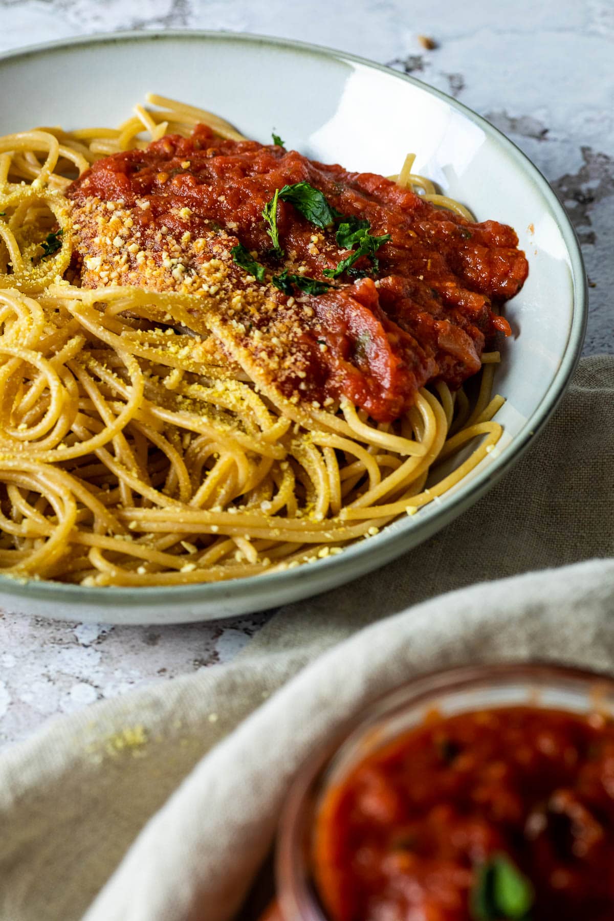 Tomaten-Sauce und Spaghetti in einer Schüssel mit veganem Parmesan