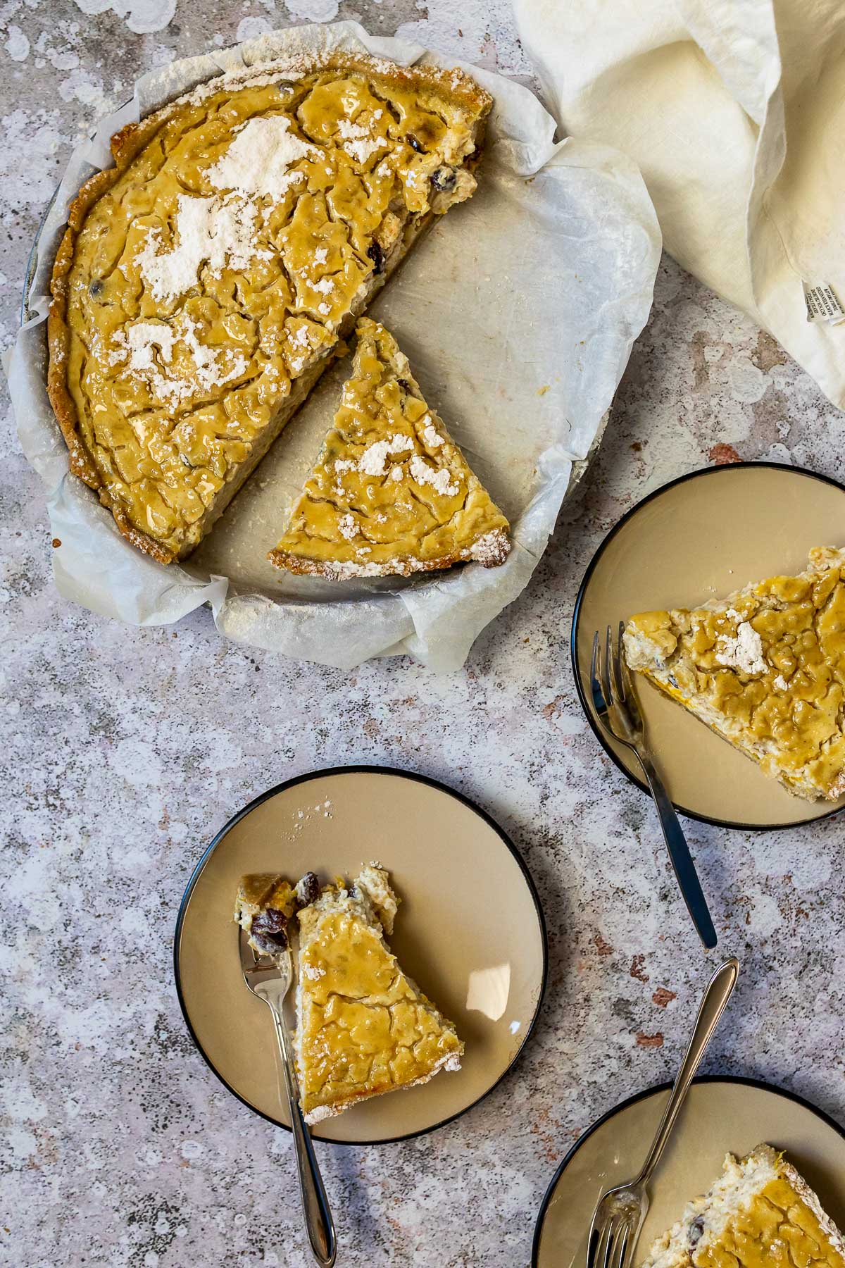 Vogelansicht auf einem Milchreis in einer Kuchenform und 3 Stück Kuchen auf drei Tellern mit drei Gabeln.