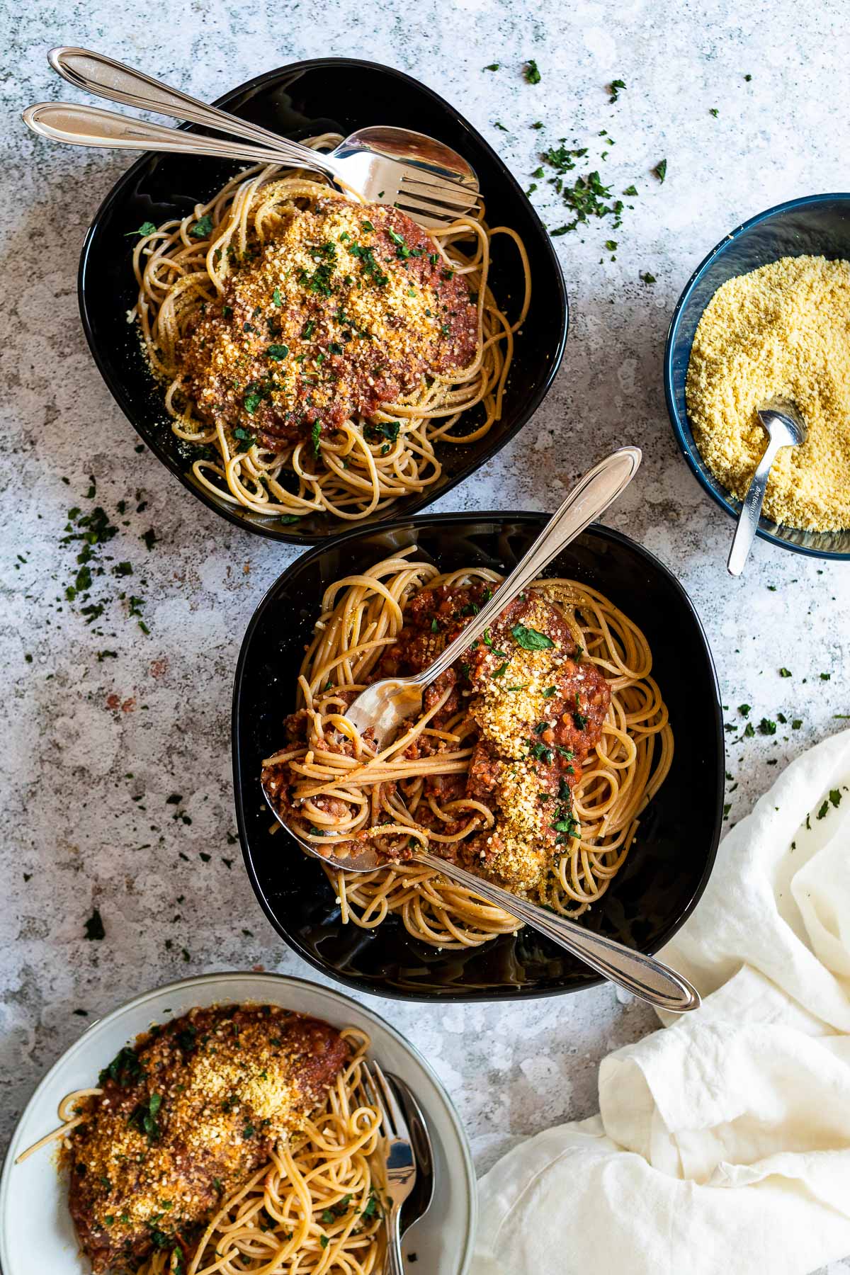 3 Nudelschalen mit Spaghetti und veganer Bolognese-Sauce mit etwas veganem Parmesan