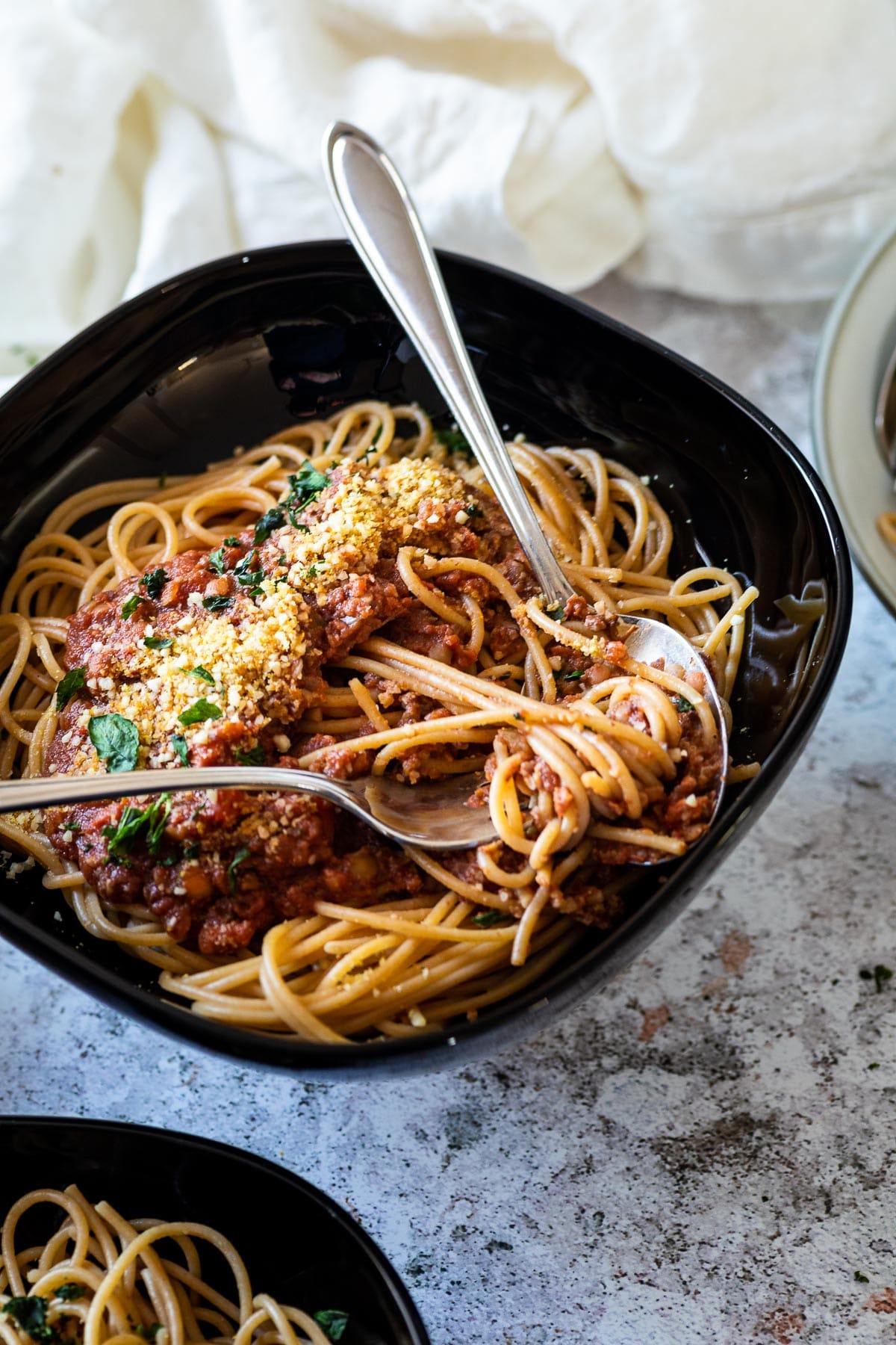 A bowl with vegan bolognese and spaghetti in focus