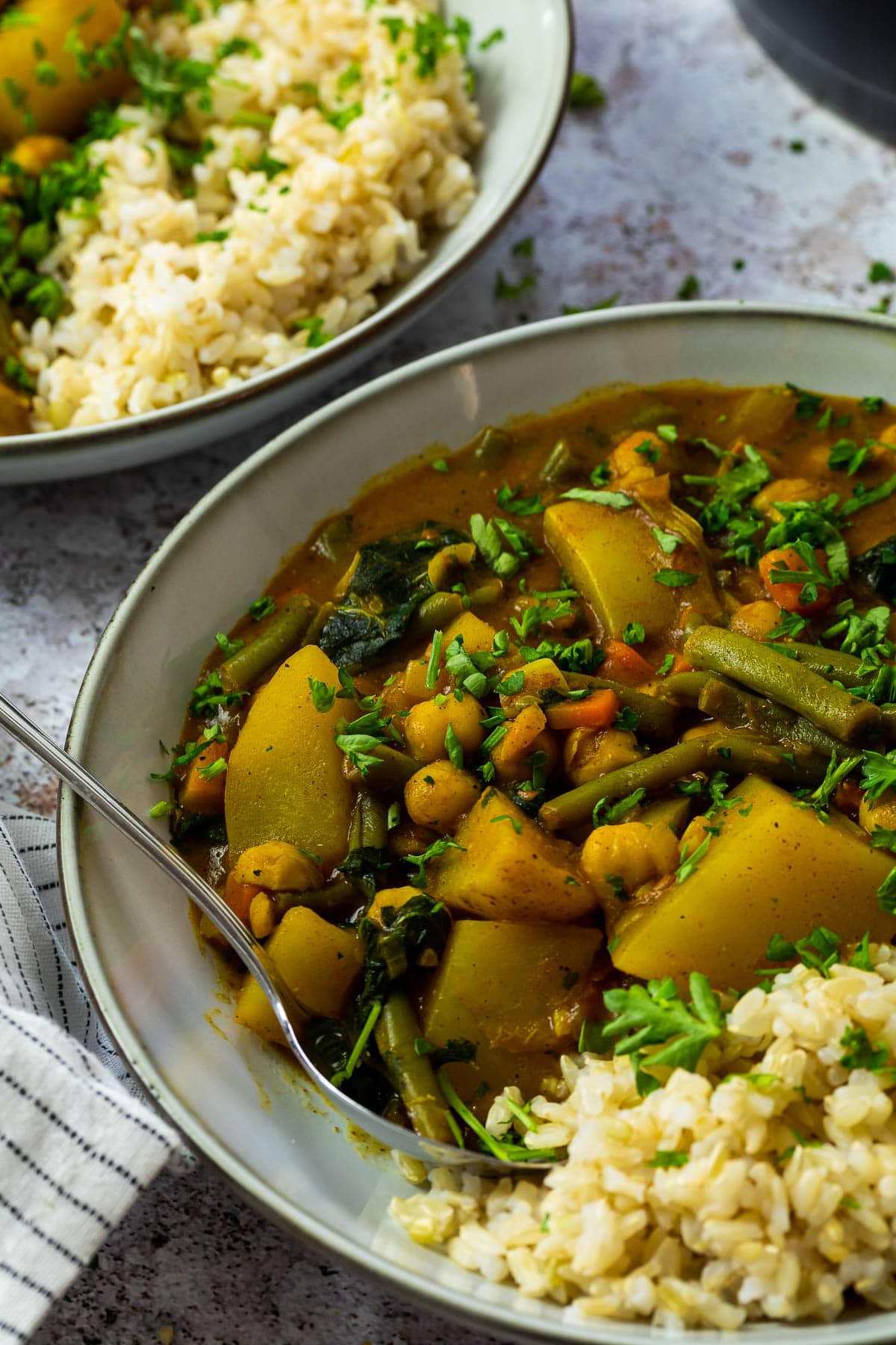 Ein Teller mit Kartoffelcurry und Reis und einem Löffel