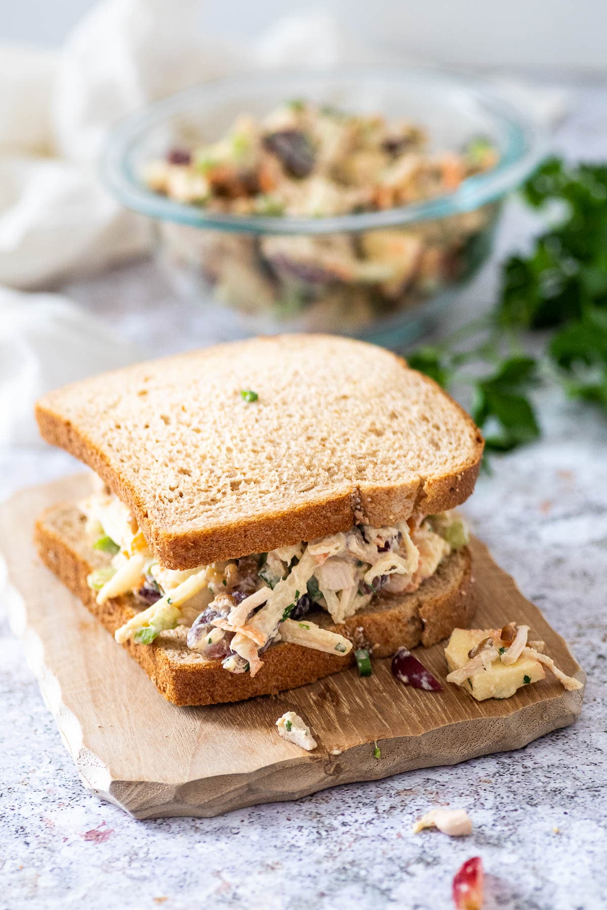 Chicken salad sandwich in the foreground and the bowl blurred in the background