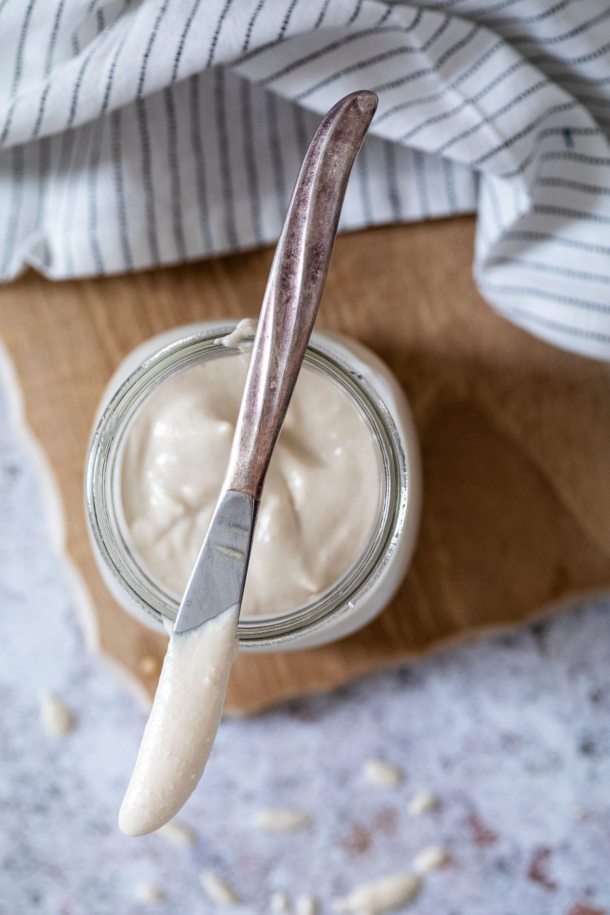 Vogelansicht auf ein Glas vegane Mayo mit einem Messer darauf liegend