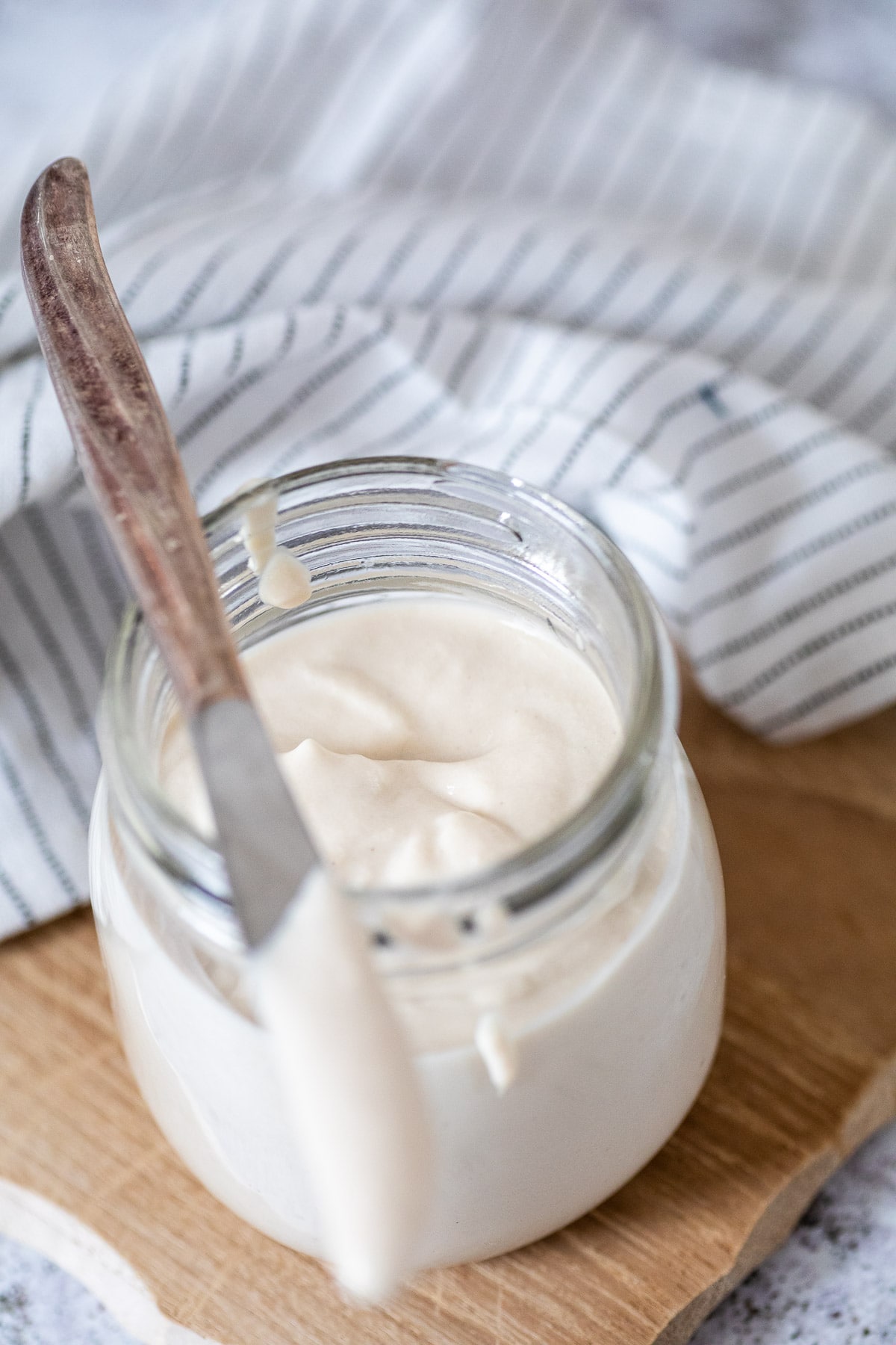 The glass of mayo in focus with the knife on top of it blurred